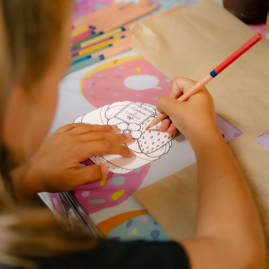 Une enfant colorie un dessin de pâtisserie pendant l'anniversaire